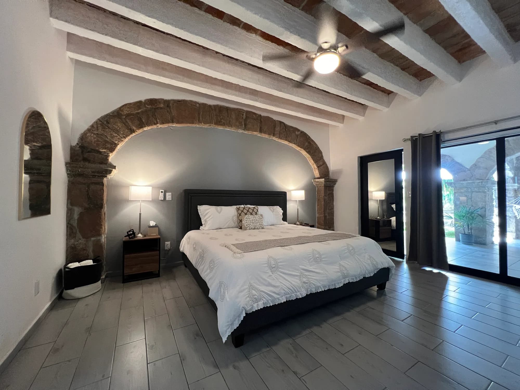 Recámara de estilo colonial en Casa Laureles con arco de piedra y vigas de madera