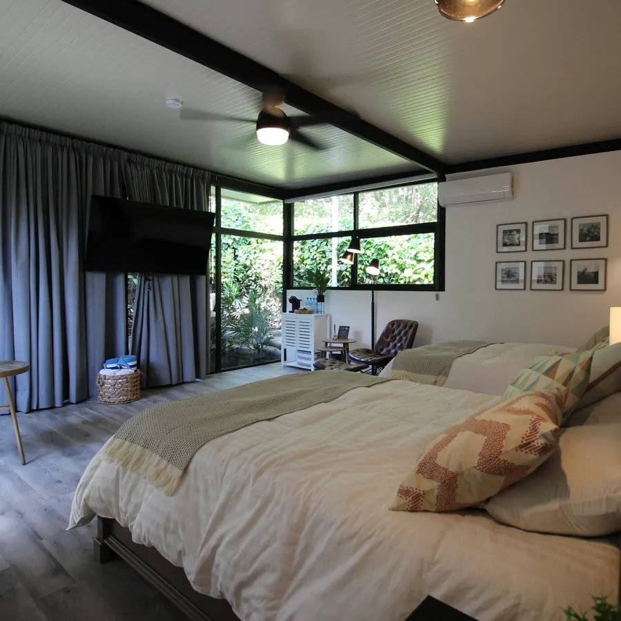 Habitación con dos camas y cortinas frente al jardín